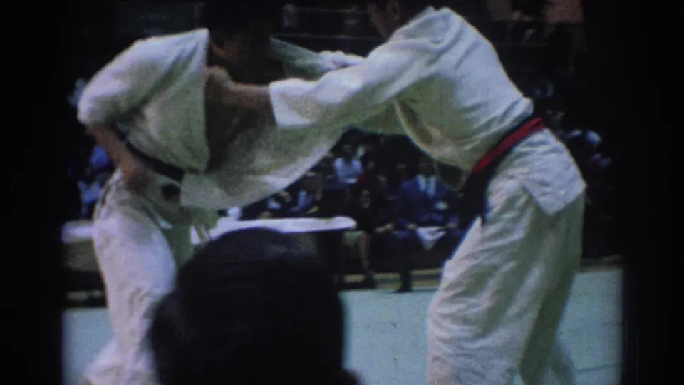 A competitor in a white gi and red belt appears to drive into a throw or clinch during the 1967 Los Angeles judo match.