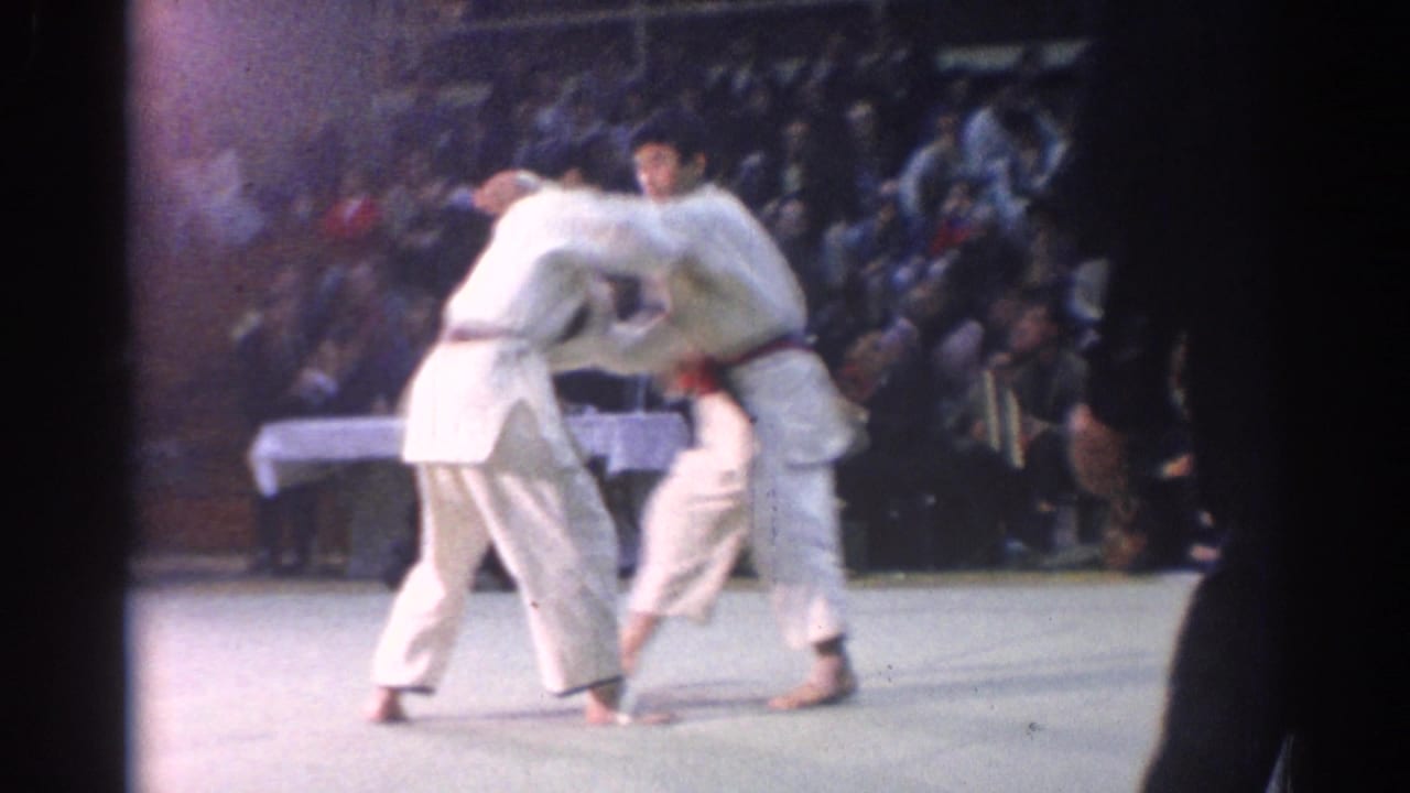 1967 Los Angeles match view with two judo competitors gripping each other on the mat as a crowd watches from the background.