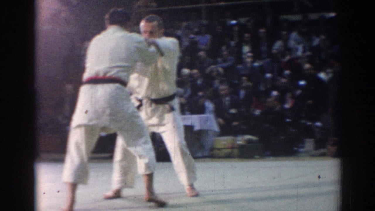 1967 Los Angeles judo match frame with two male competitors facing each other on a gym mat before a large audience.