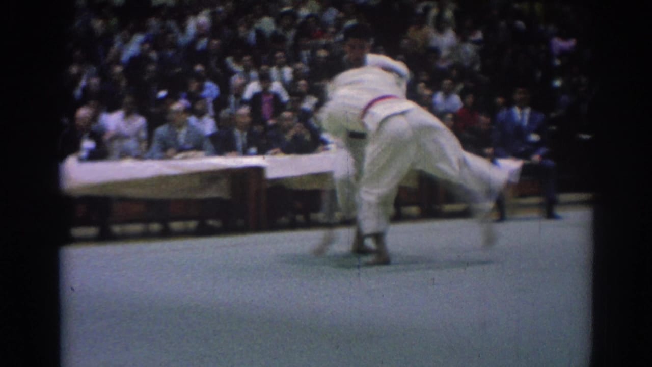 A 1967 tournament frame captures a karate competitor being pulled off balance during a throw attempt on the mat.