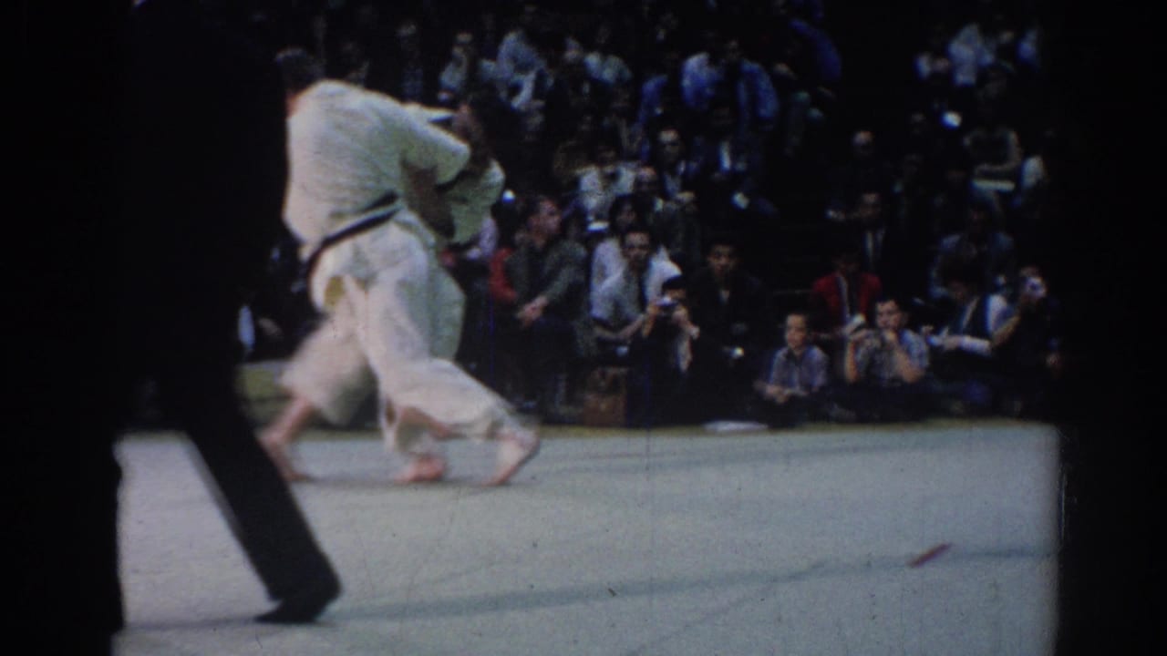 At the end of the 1967 Los Angeles clip, the judo competitors move together across the mat while an official passes in front of the camera.