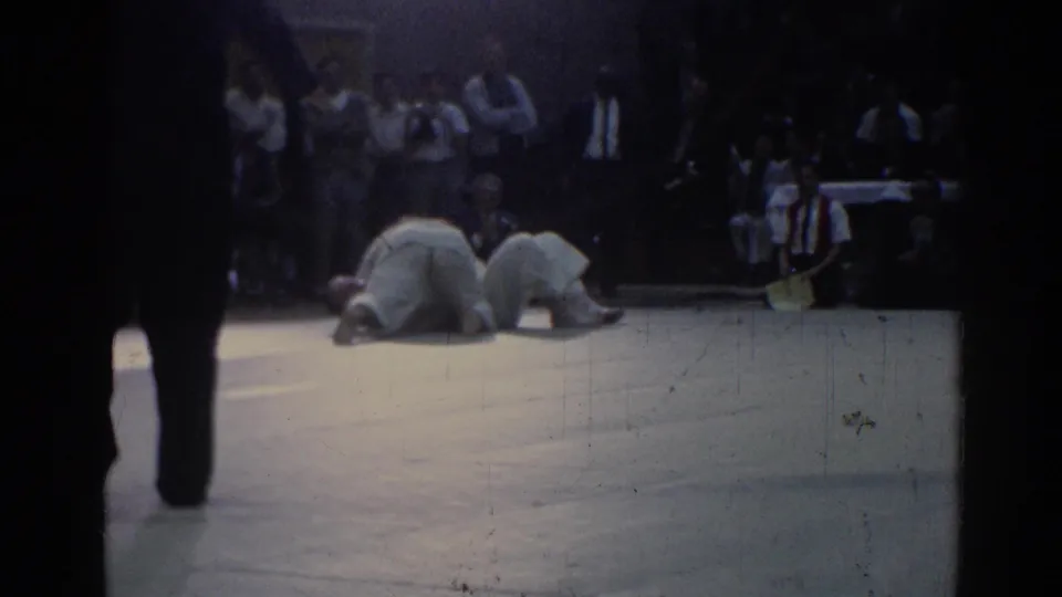 1967 Los Angeles judo match footage showing two athletes down on the mat with a crowd watching from the stands.