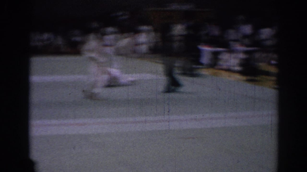 Motion-blurred 1967 Los Angeles tournament frame with a karate competitor thrown or falling as an official stands nearby.