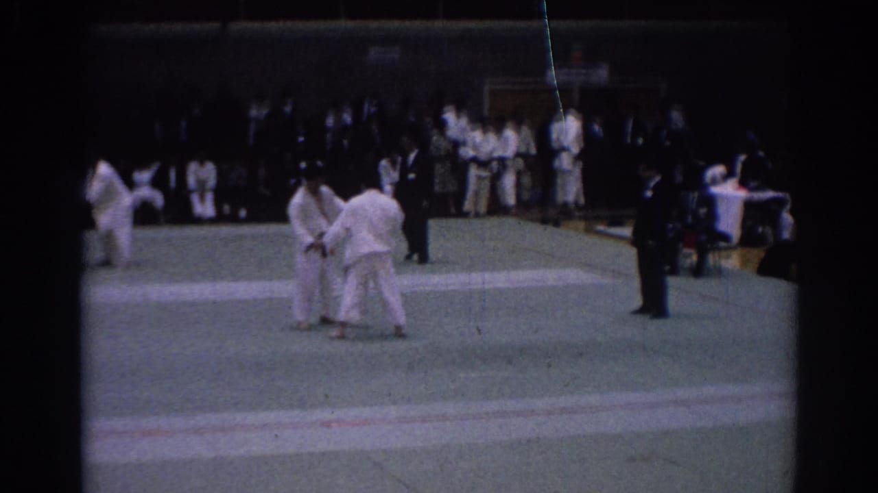 1967 Los Angeles 8mm footage frame of two karate competitors beginning an exchange on a gymnasium mat.