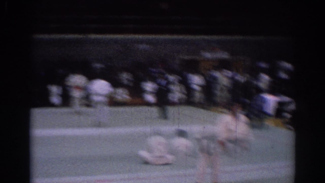 Motion-blurred 8mm frame from the 1967 Los Angeles karate tournament, with a fighter moving across the mat before seated spectators.