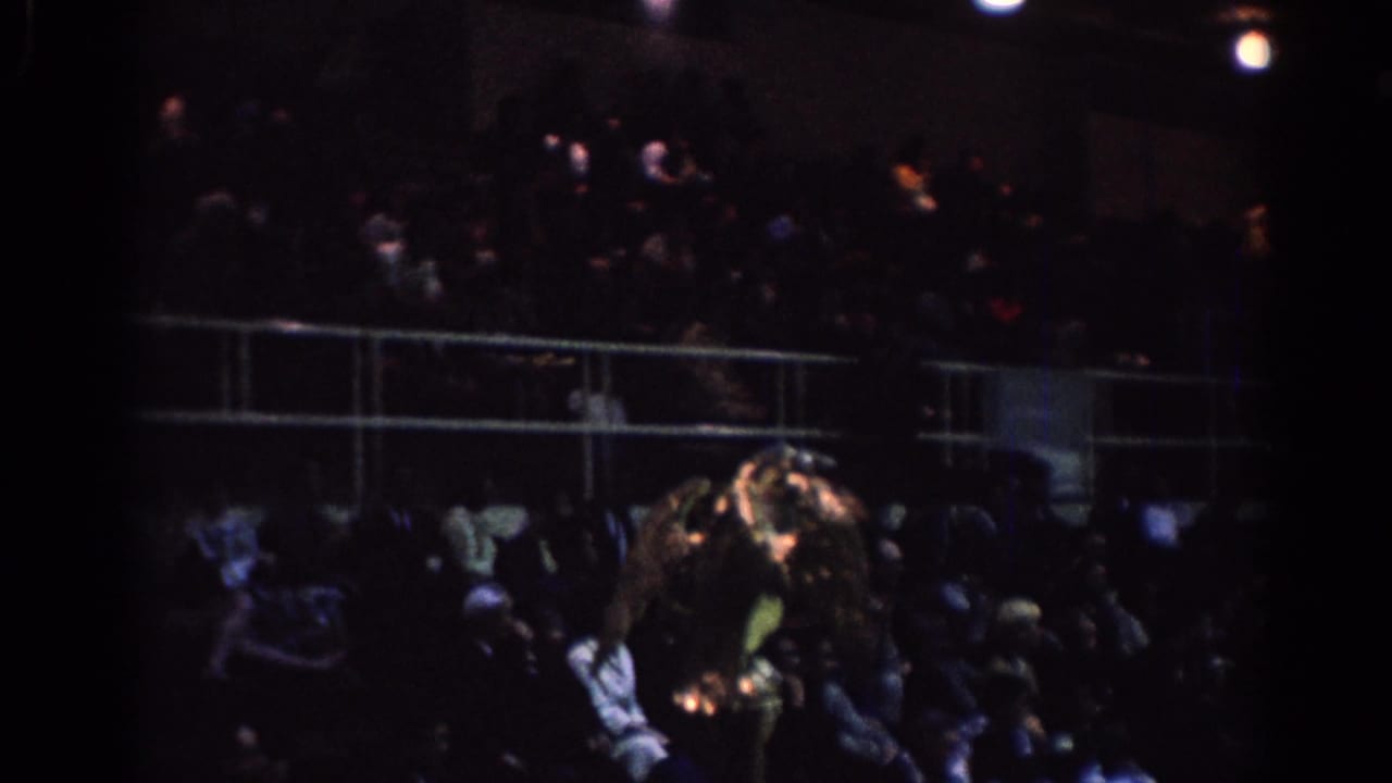 Crowded indoor bleachers with a bright gold object near the foreground.