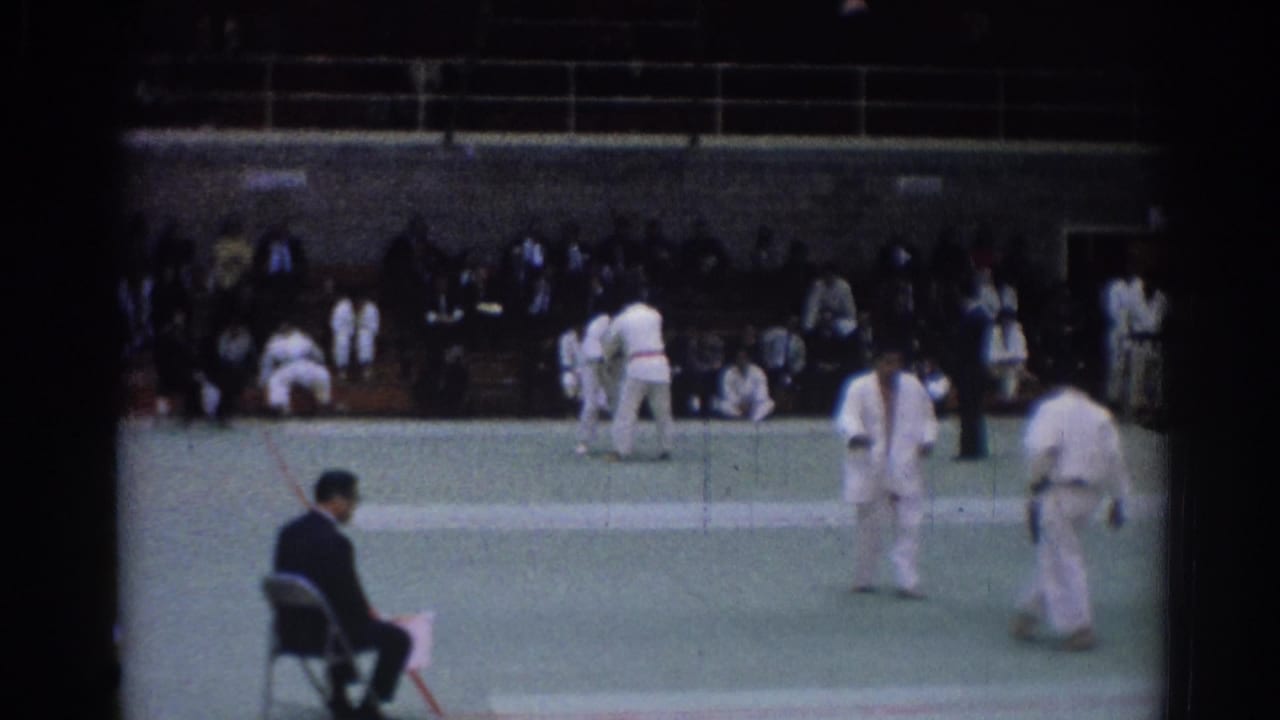 1967 Los Angeles indoor judo footage showing athletes in white gi between exchanges on a green competition mat.