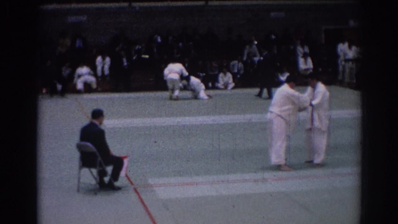 1967 Los Angeles judo competition frame with two athletes in white gi facing each other near a seated referee.