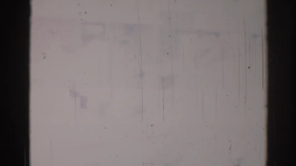 1967 Los Angeles 8mm frame detail with pale exposed film, dark gate edge, vertical scratch lines, dust specks, and faint blue-purple staining.