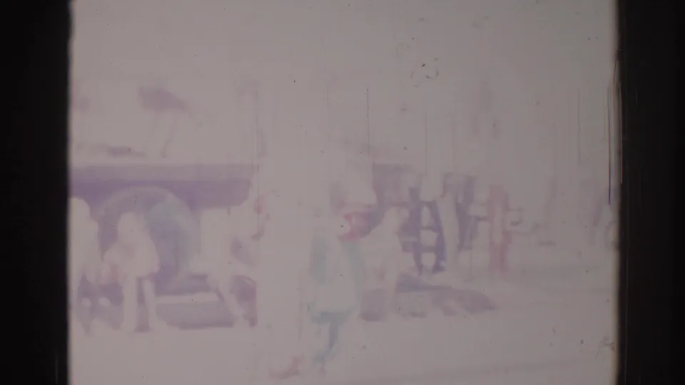 Washed-out 1967 Los Angeles parade view with faint figures, a possible float or vehicle, and strong 8mm scratches.