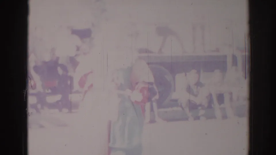 Faded 8mm parade frame from Los Angeles in 1967, showing costumed figures and a wheeled vehicle or float in bright daylight.