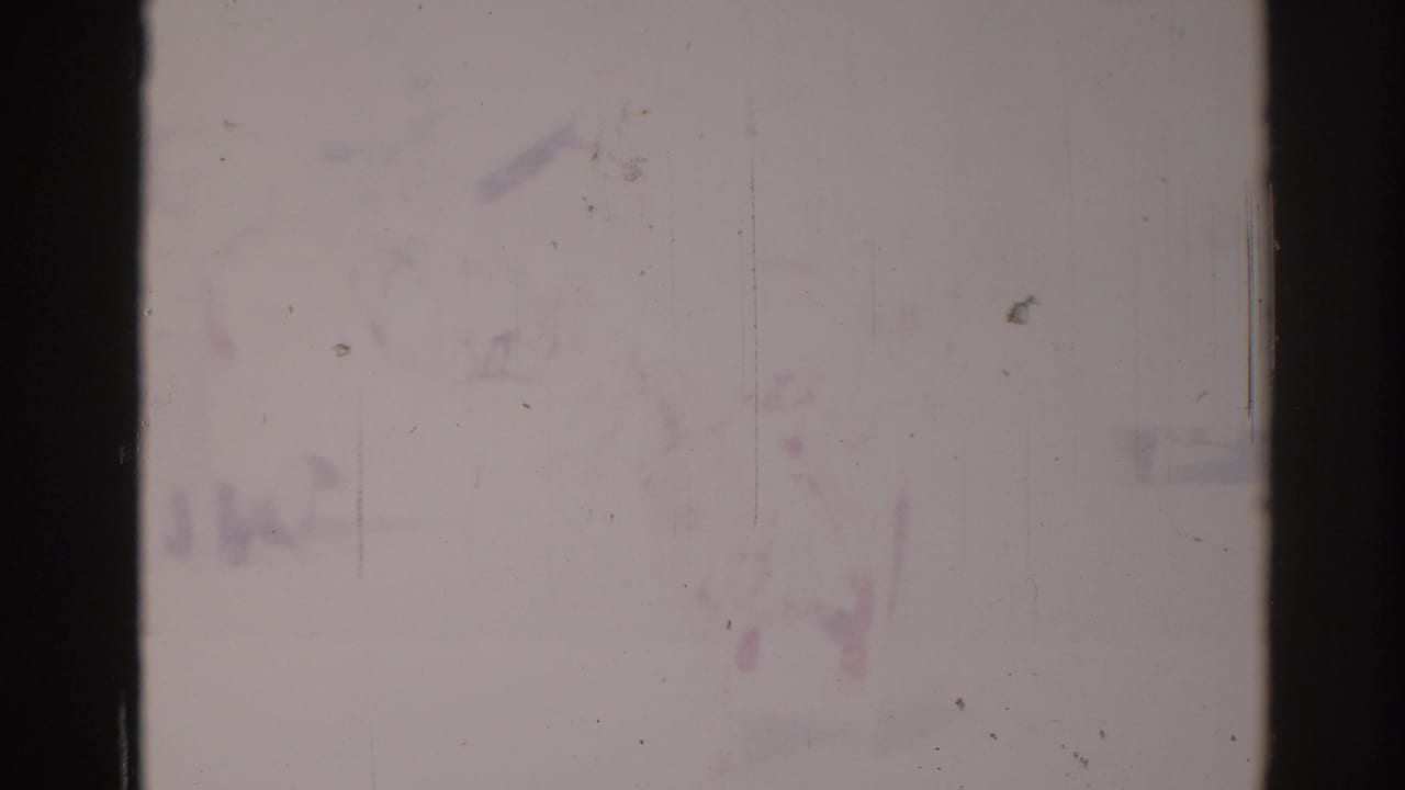 Faded street view with a barely visible horse and rider in bright washed-out 8mm footage.