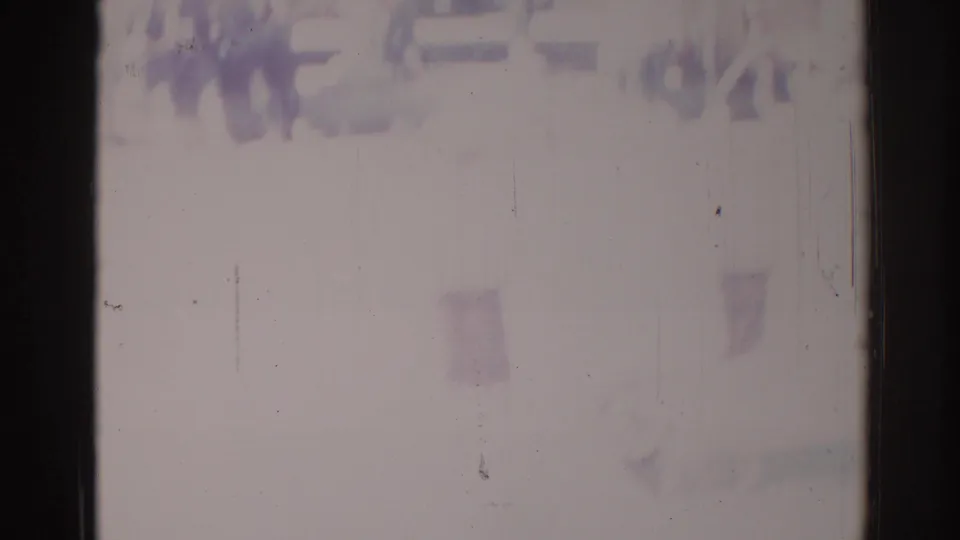 Faded 1967 Los Angeles 8mm frame with indistinct spectators at the top edge and little detail visible below.