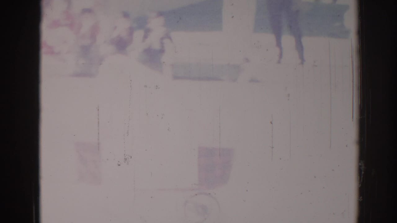 Overexposed frame with vague figures and a faint carriage-like shape near the upper area.