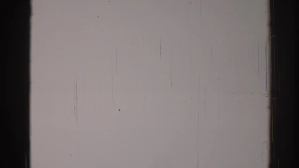 1967 Los Angeles 8mm frame showing a pale wall bordered by dark film edges, with dust, grain, and faint vertical scratches.