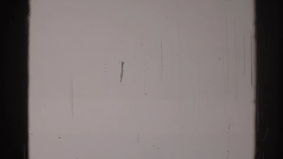 1967 Los Angeles 8mm frame showing a pale wall with dark film edges, surface grain, vertical scratches, and a small irregular mark left of center.