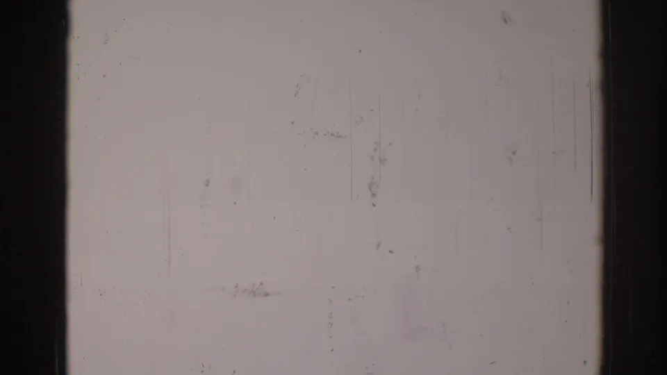 1967 Los Angeles 8mm frame showing a light blank film area, dark edge, central divider, dust specks, vertical scratches, and grain.