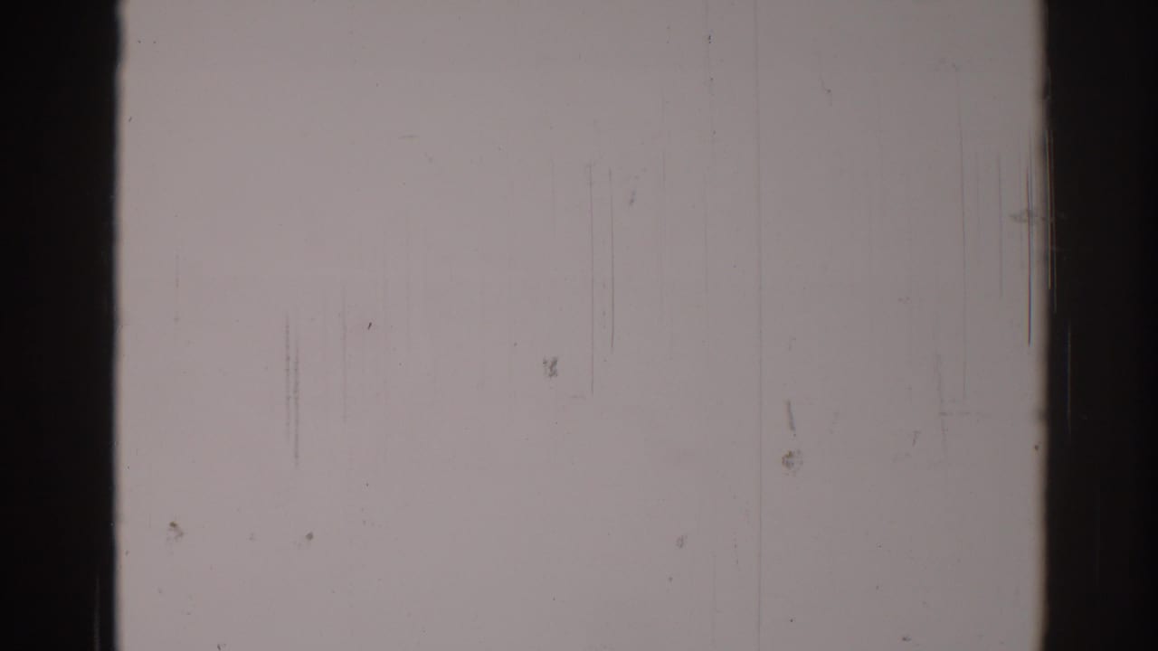 Pale blank film area divided by dark vertical borders, with fine scratches and dust.