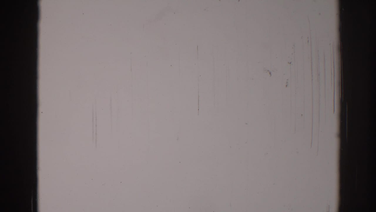 Blank pale 8mm frame with dark vertical edges, scratches, dust, and grain.
