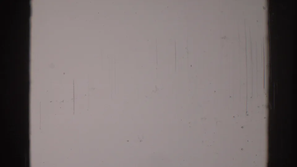 1967 8mm home-movie still showing a muted blank film frame with dark borders, vertical scratches, dust specks, and grain.
