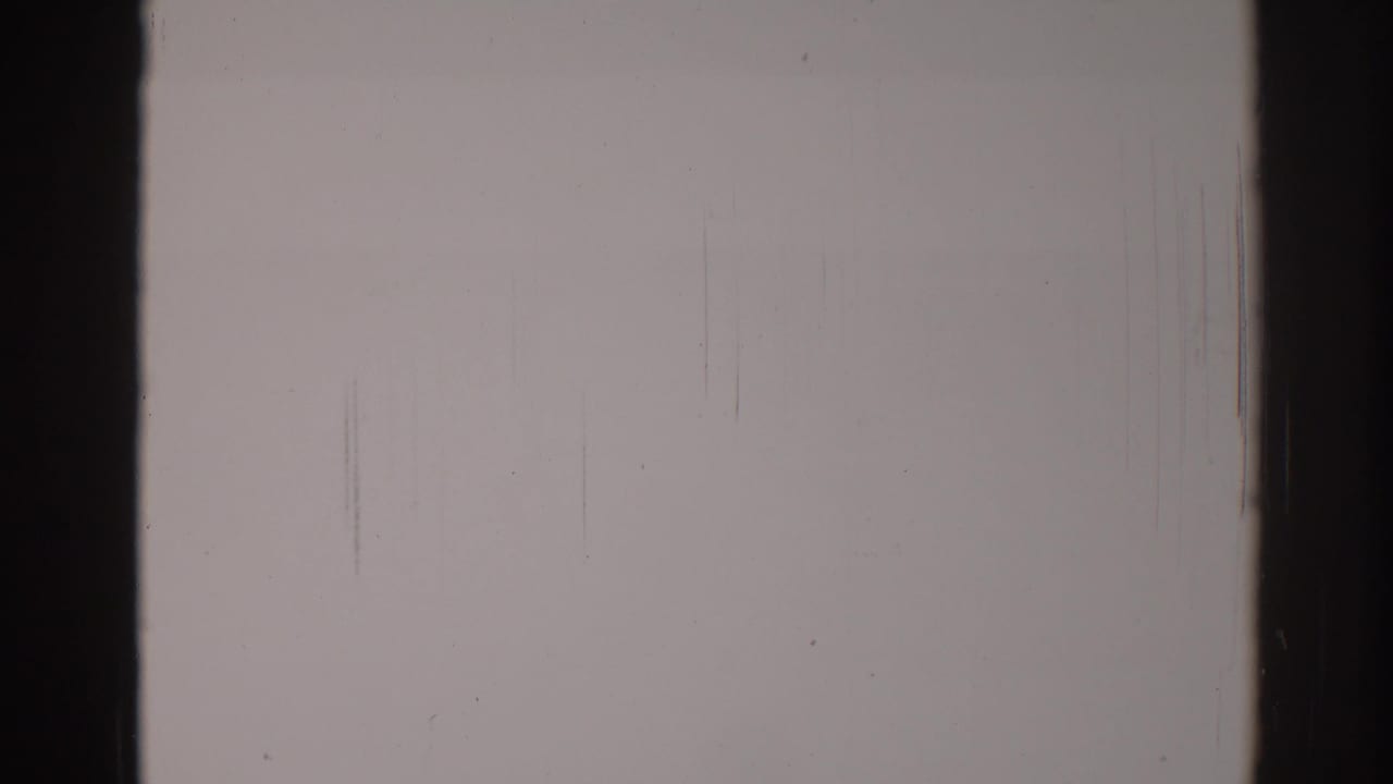 Blank pale film frame with dark vertical edges, fine scratches, and dust specks.