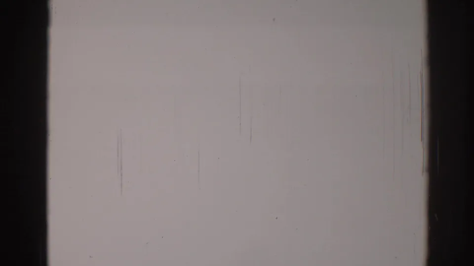 1967 Los Angeles 8mm blank film frame with dark gate edges, faint vertical scratches, dust, and uneven pale exposure.