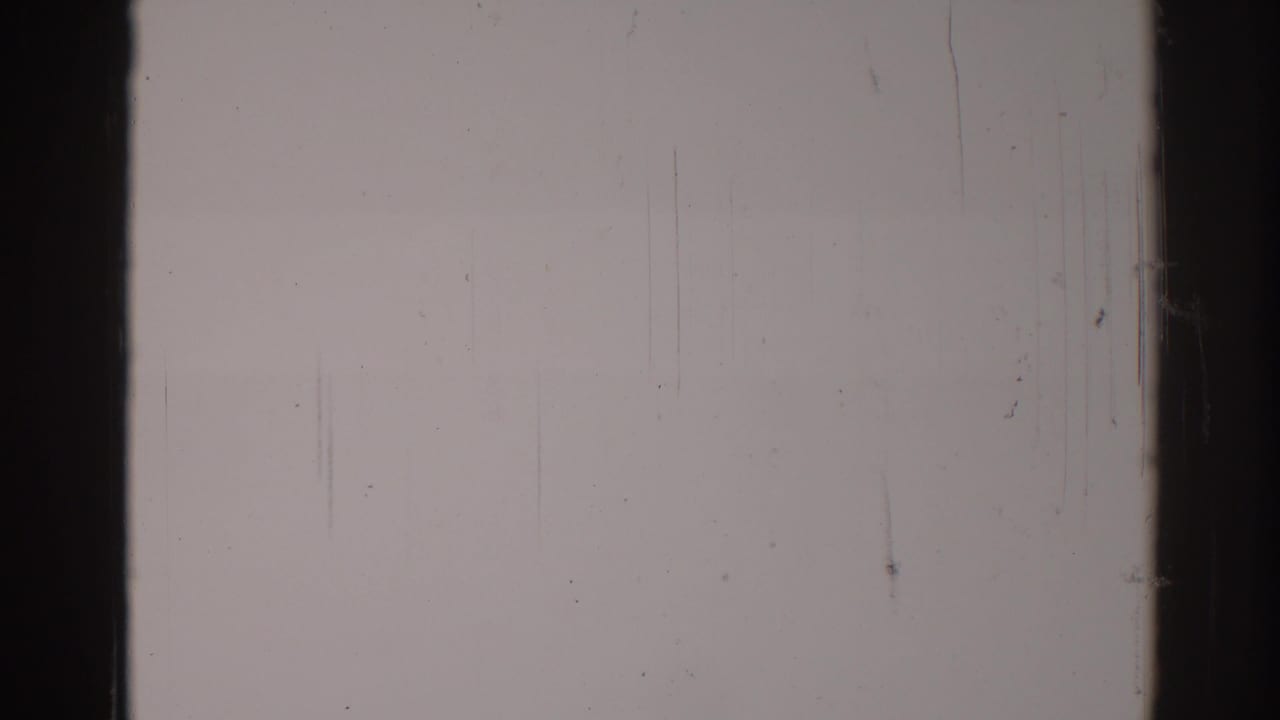 Blank pale film frame divided by a dark vertical film bar with scratches and dust.