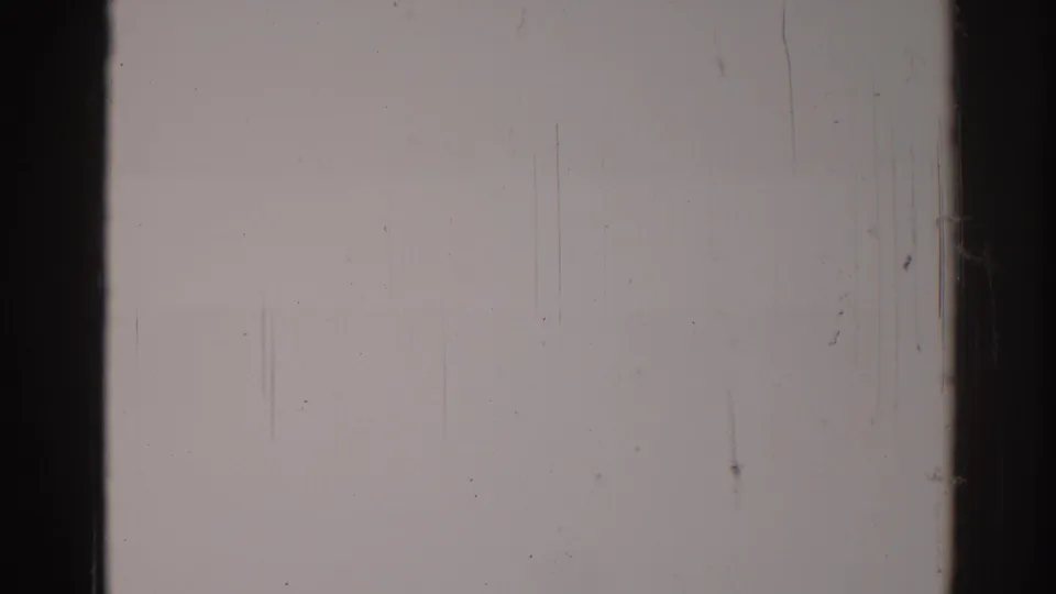1967 Los Angeles 8mm blank frame showing a dark vertical film bar, pale exposure, dust specks, and fine surface scratches.