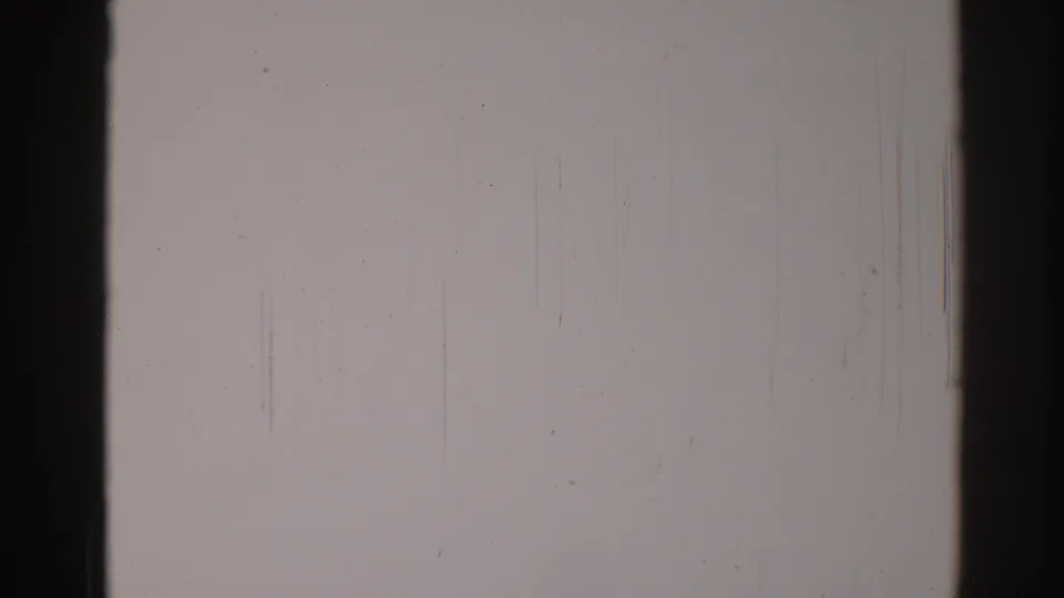 1967 Los Angeles 8mm blank frame with a dark edge, faint vertical scratches, dust marks, and muted white film density.