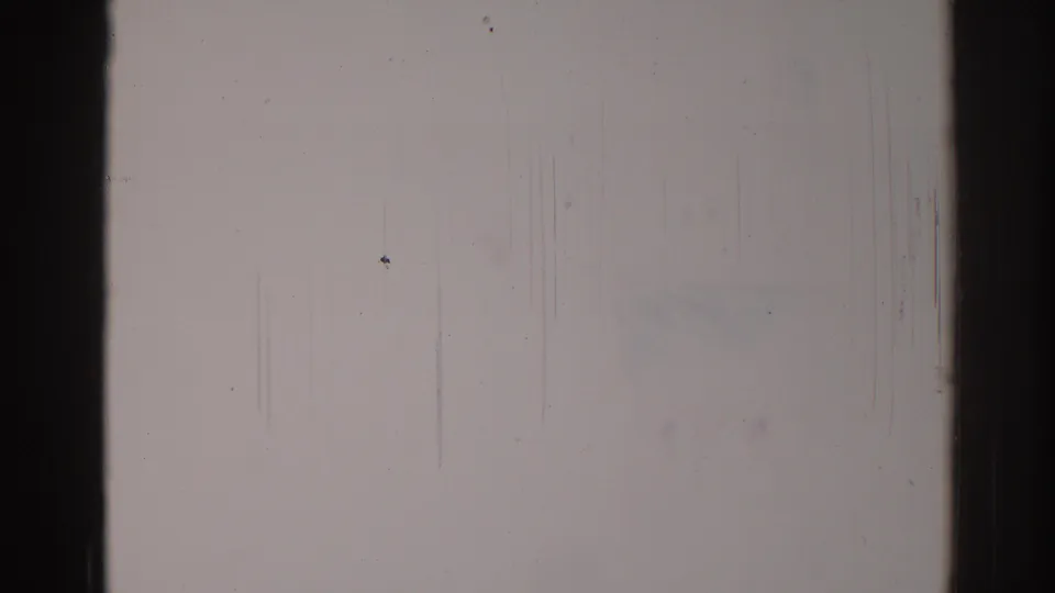 1967 Los Angeles 8mm blank film frame showing edge shadowing, dust specks, faint scratches, and subtle exposure variation.