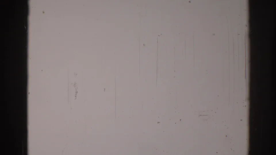 1967 Los Angeles 8mm frame showing a pale gray field with dark film edges, fine scratches, dust, and soft grain.