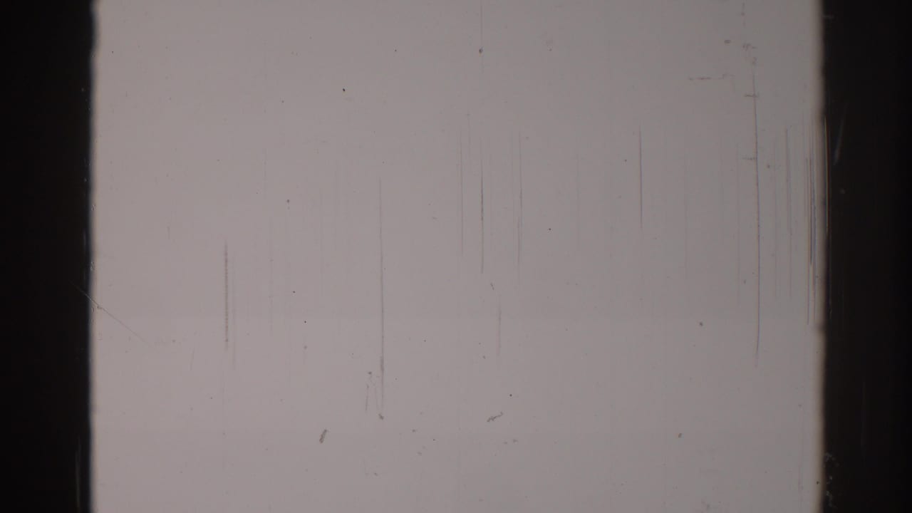 Pale overexposed film frame with dark vertical edges and faint scratches.