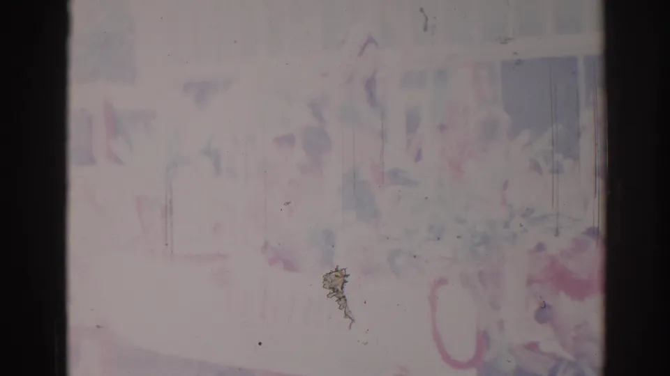 Faded 1967 Los Angeles 8mm frame where faint people and possible structures emerge through heavy overexposure, scratches, and color shift.