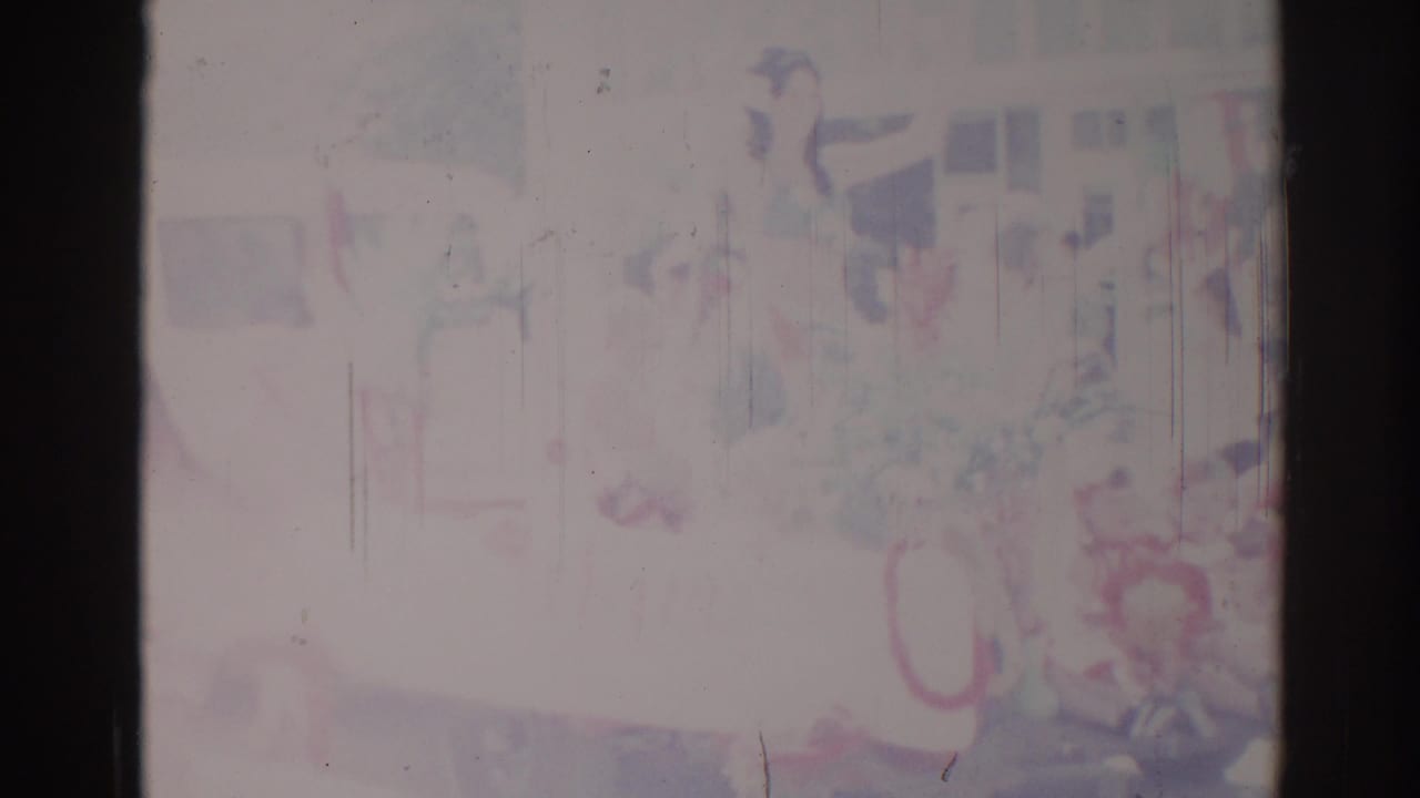 Soft, faded parade frame with uniformed people and film scratches.