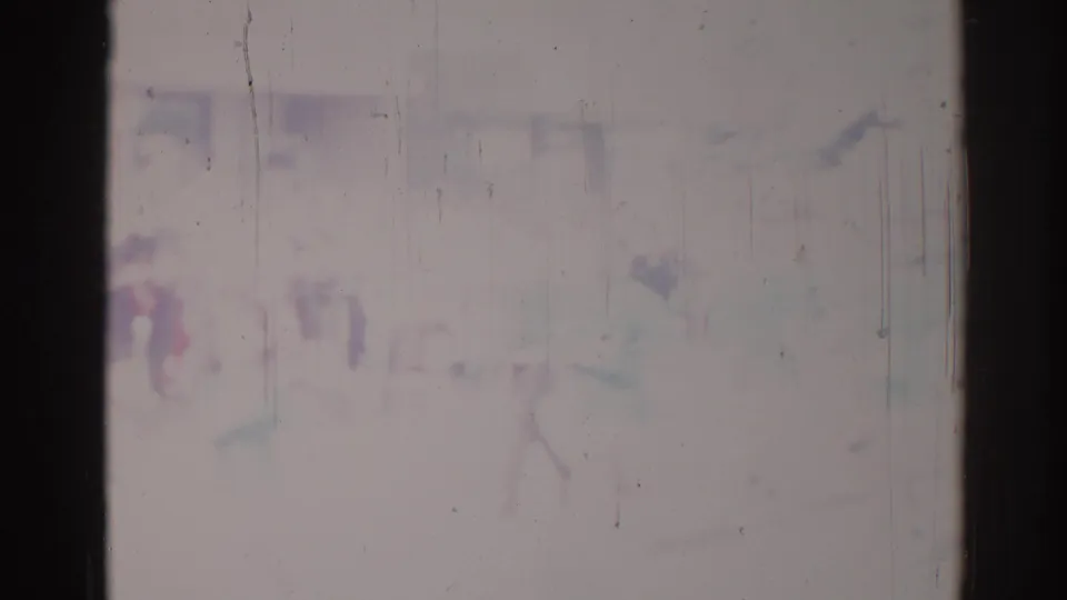 Degraded 8mm frame from a 1967 Los Angeles parade, with indistinct figures, pale color, and visible scratches across the image.