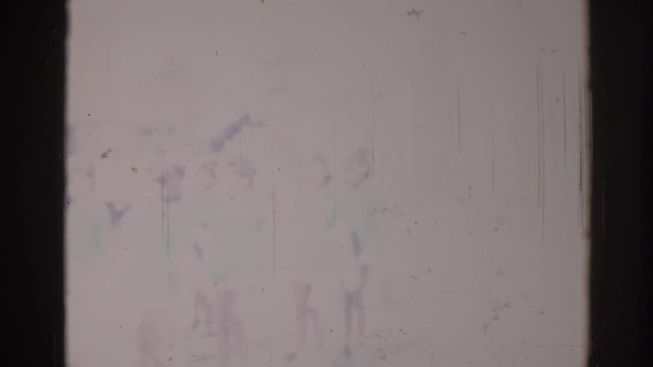 Faded film frame with indistinct public-event shapes and dark 8mm borders.