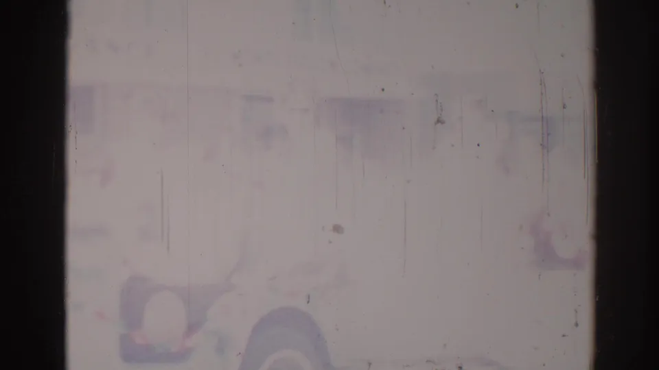 Degraded 1967 Los Angeles 8mm frame with a faint vehicle- or float-like shape and muted purple-blue fading.