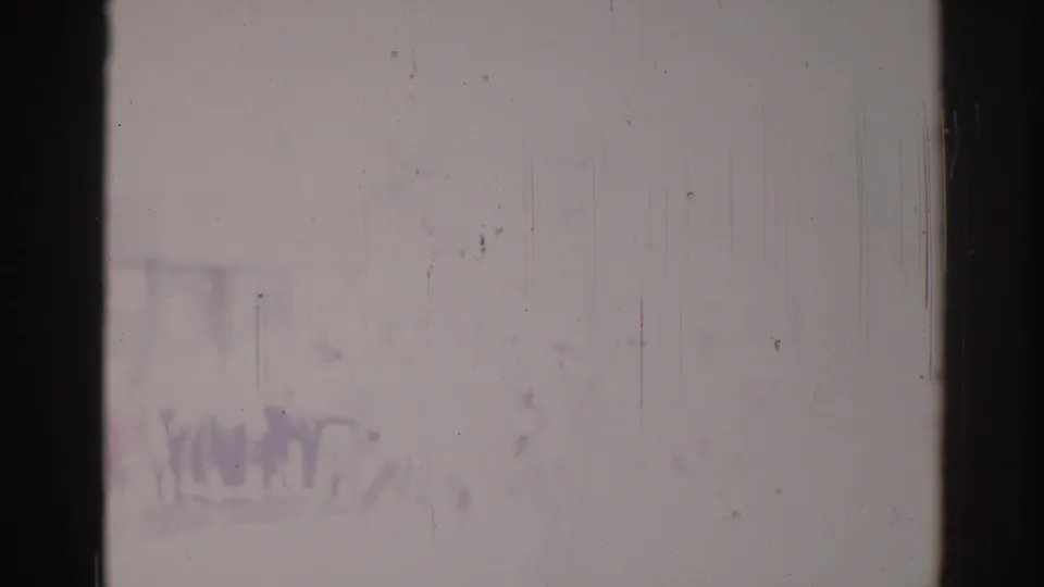 Heavily faded 1967 Los Angeles 8mm frame with faint crowd-like marks and strong scratches across the image.