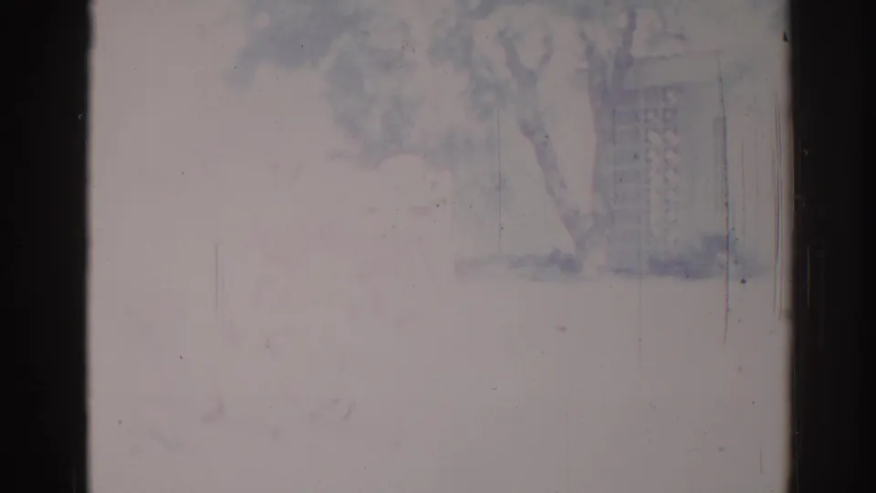1967 Los Angeles 8mm frame with a pale, faded exterior view, faint tree and building forms, heavy scratches, and dark vertical film edges.