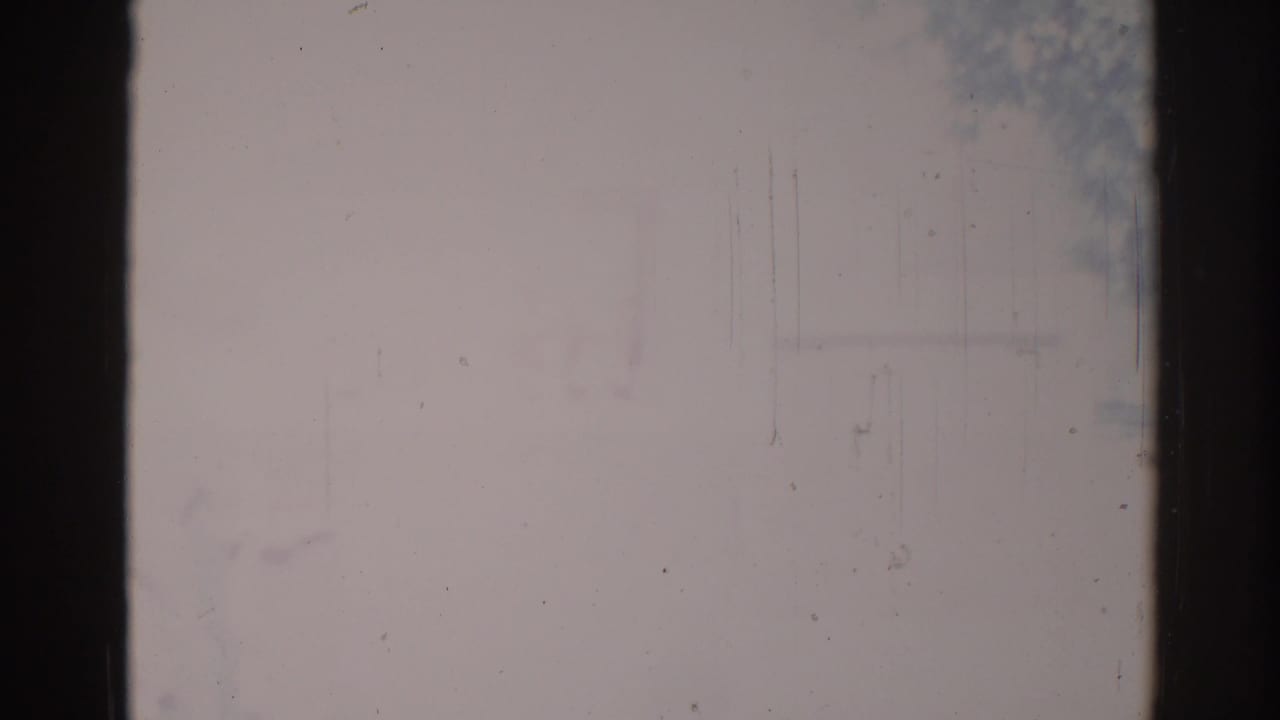 Faded outdoor view divided by dark vertical borders and surface scratches.
