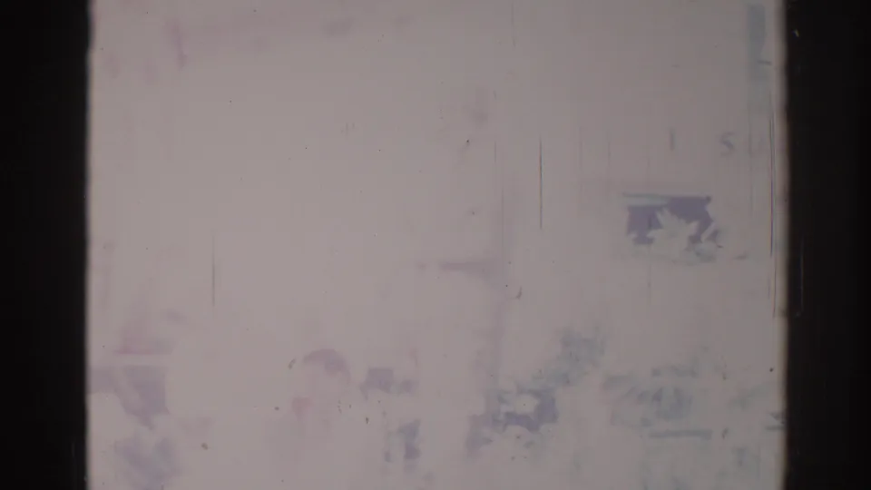 Obscured 8mm frame from the Los Angeles 1967 clip, showing dark borders, pale exposure, scratches, and indistinct lower-edge forms.