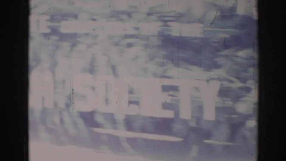 Faded 1967 Los Angeles 8mm frame showing a decorated parade float or vehicle with bold white lettering.