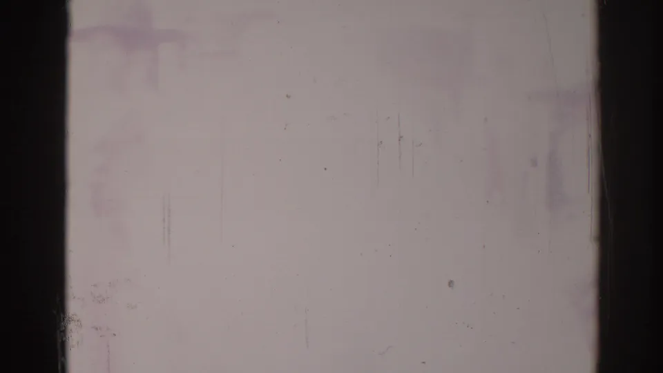 Overexposed 8mm frame from the Los Angeles parade clip with faint street forms and prominent aging marks on the film.