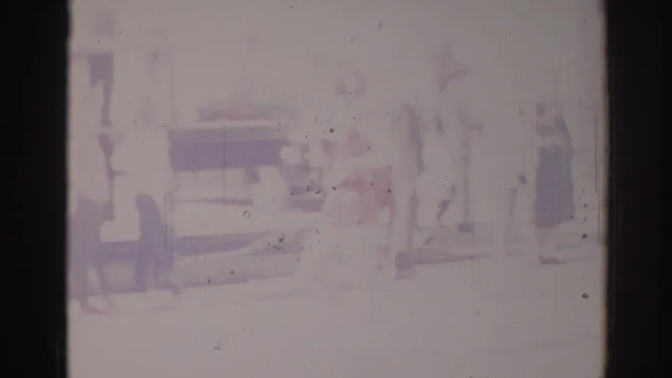 1967 Los Angeles home-movie frame showing a very faded street parade view with blurred figures and a vehicle shape.
