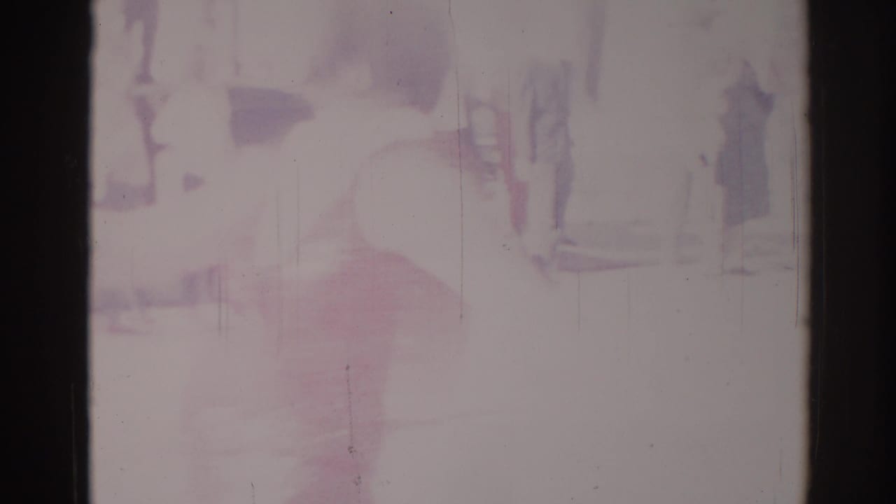 Overexposed street view with faint standing figures and a reddish shape near the center.