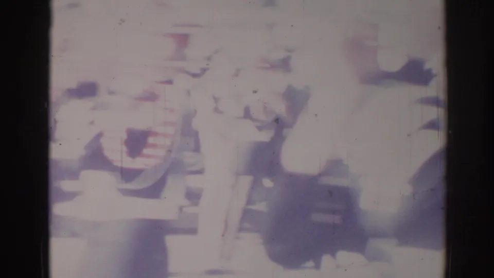 1967 Los Angeles home-movie frame with a blurred person in light clothing near street activity and heavy film fade.