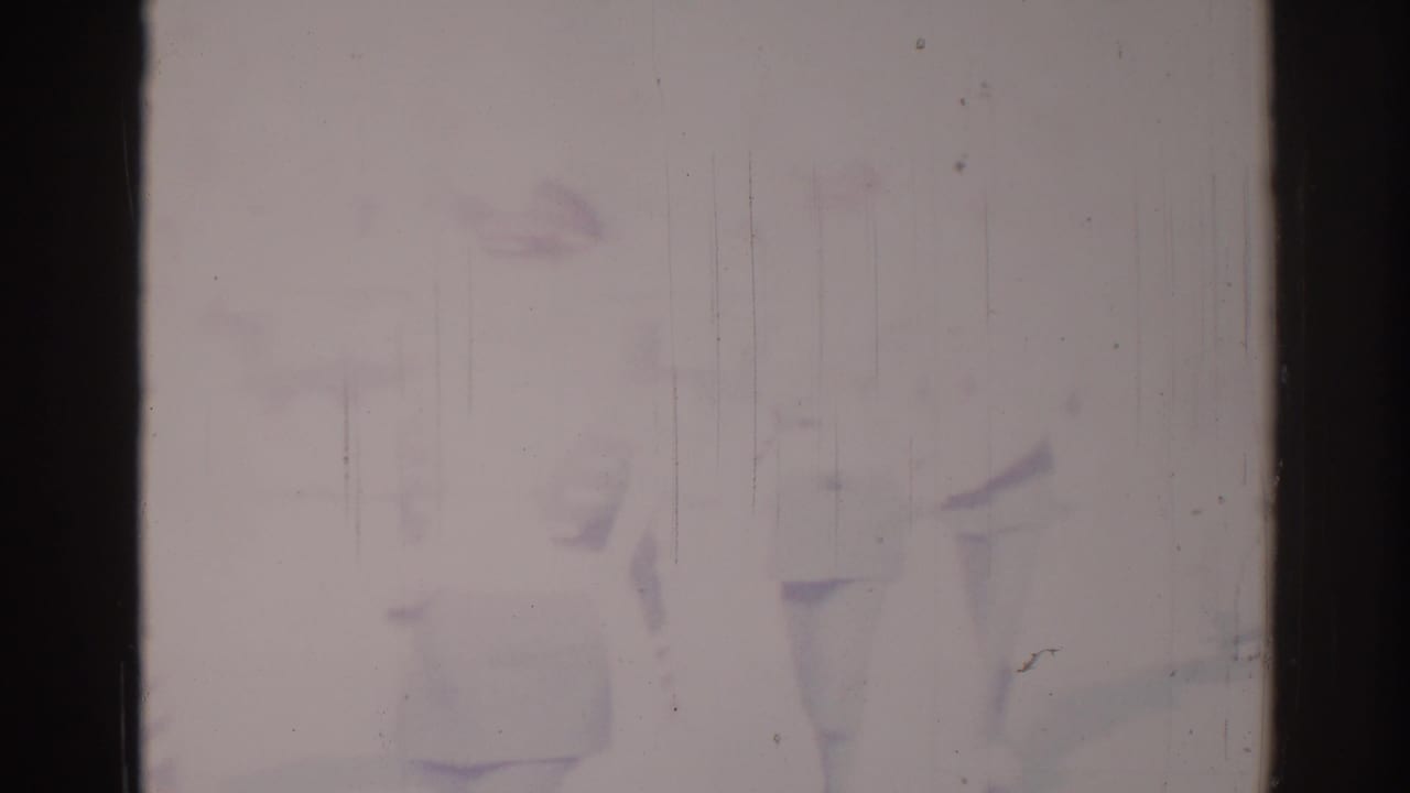 Overexposed 1967 Los Angeles home-movie frame with faint figures, a possible sign, and heavy film wear obscuring detail.
