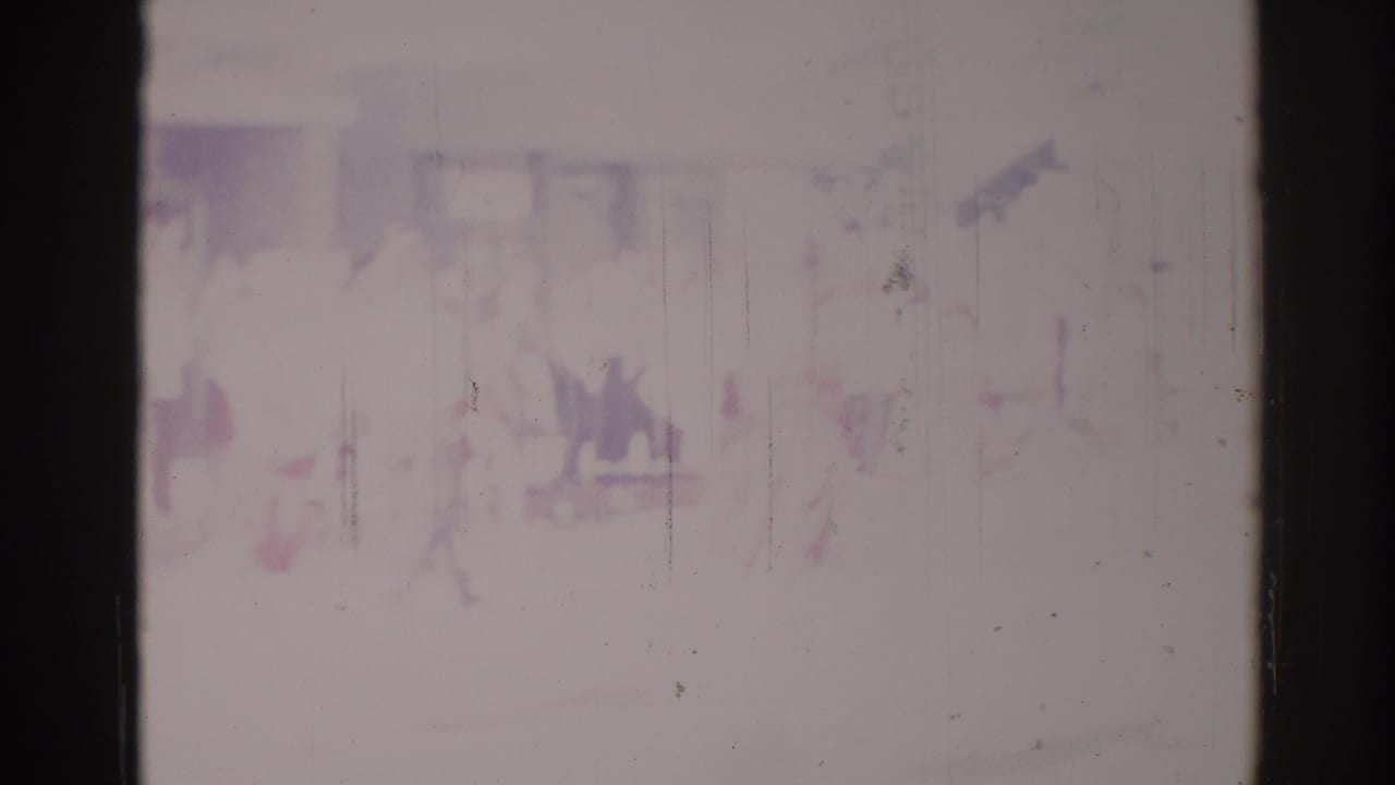 Soft, faded 1967 Los Angeles frame with indistinct people near a building frontage and possible sign elements at the edge.