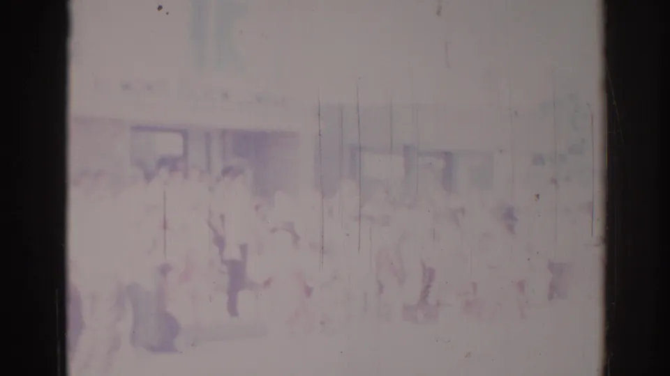 Faded home-movie frame from Los Angeles shows a blurry parade or procession with indistinct figures and spectators along the street.