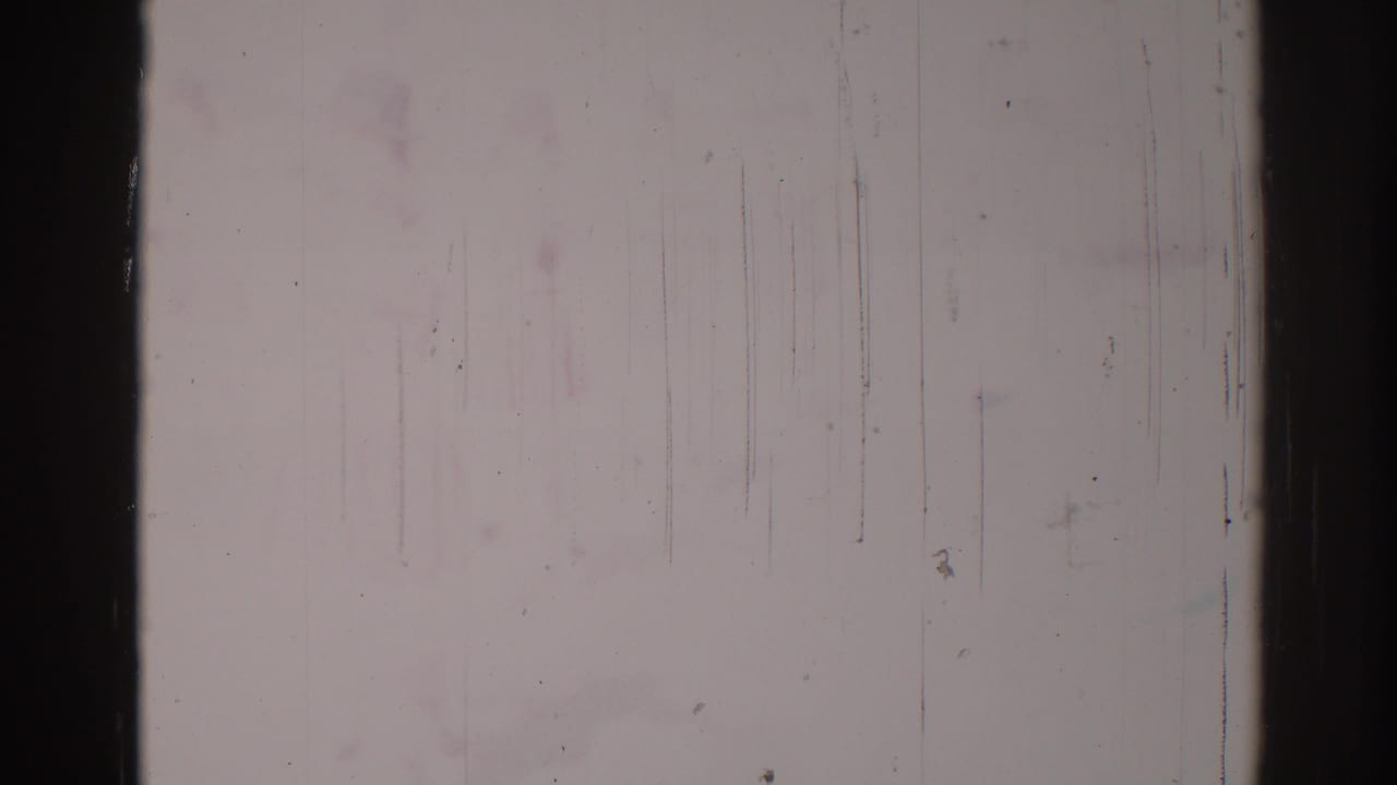 Nearly washed-out 1967 Los Angeles 8mm frame with faint activity traces, dark film borders, and visible surface abrasion.